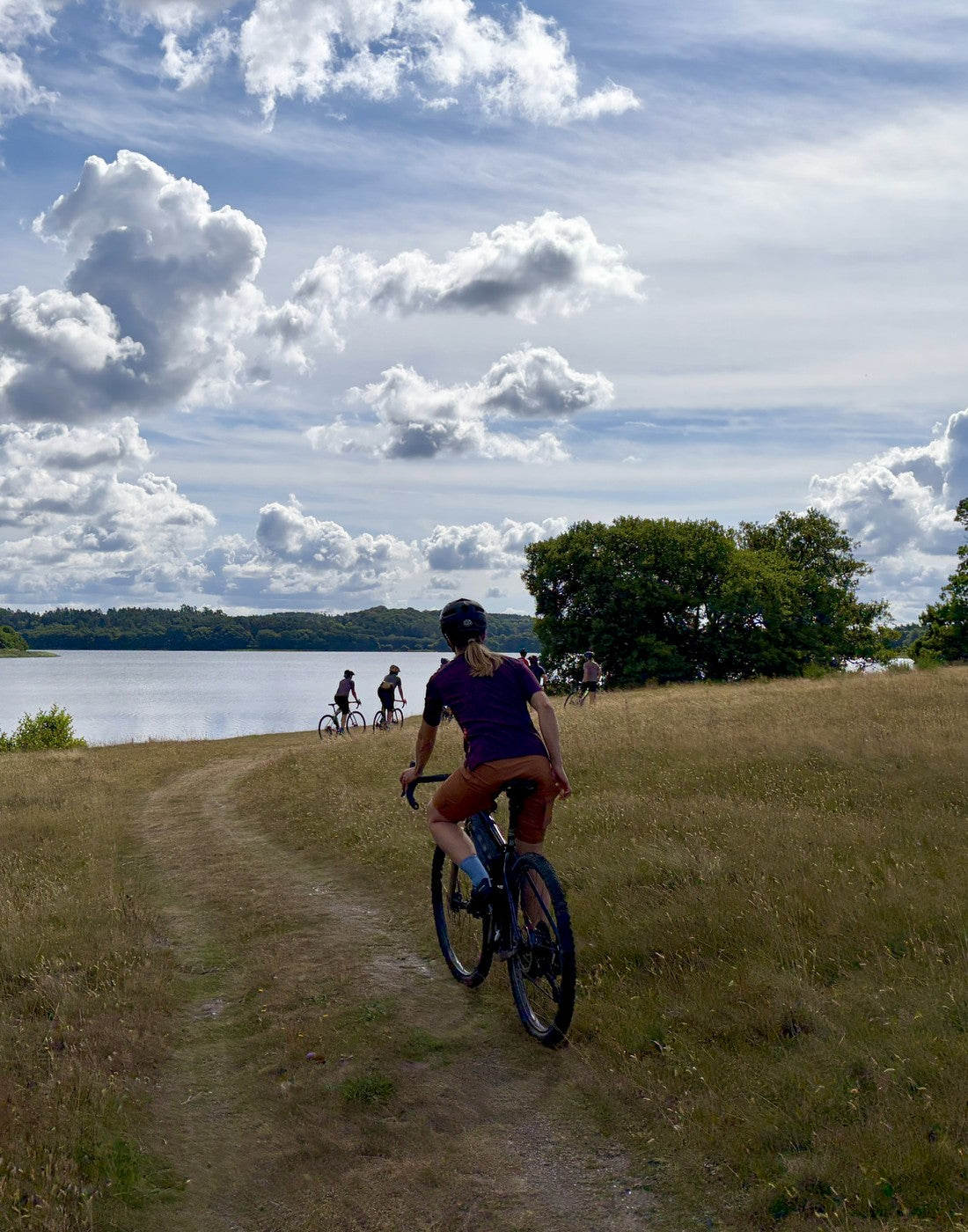 Gruppe på gravelcykler på en sti langs en sø en sommerdag